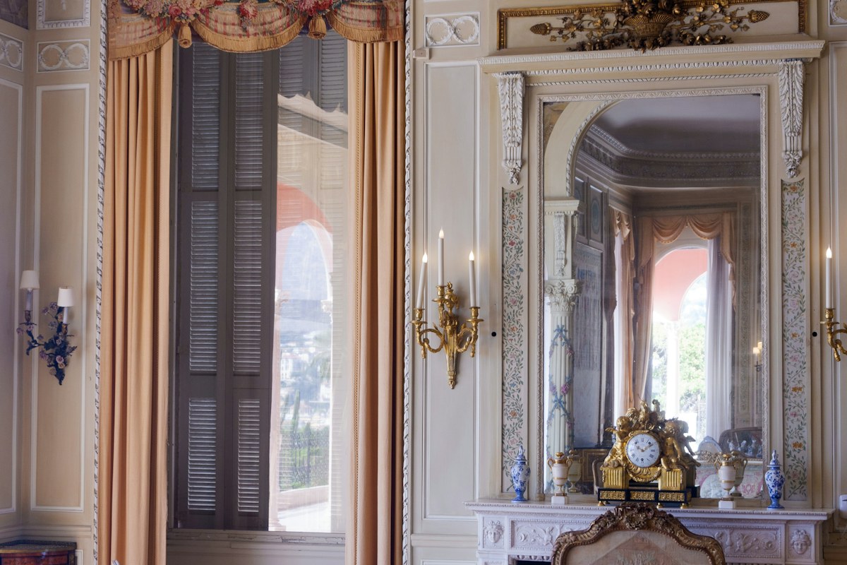 An ornate museum drawing room with gilded chairs and a fireplace