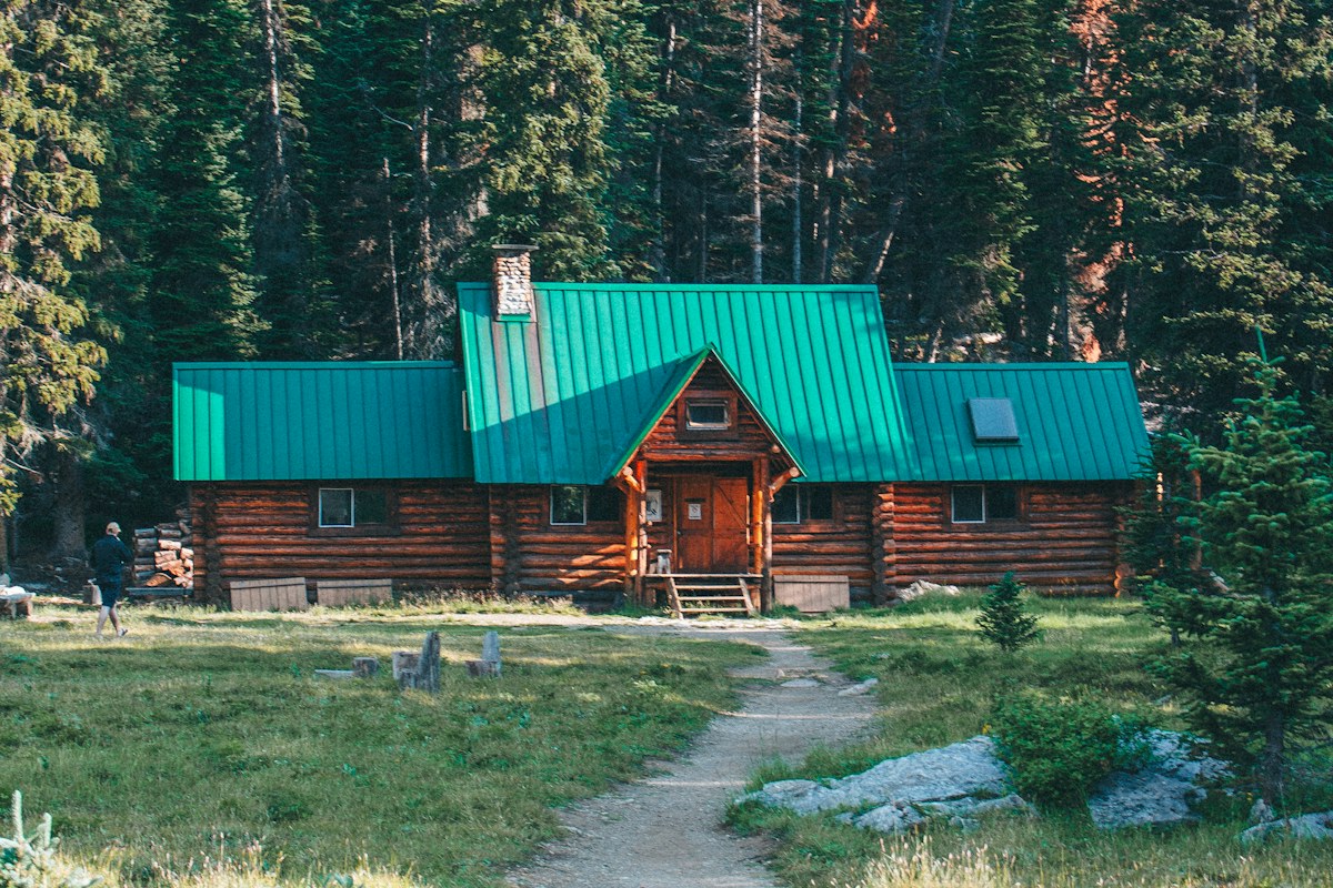 A wooden cabin among evergreen forest and mountains