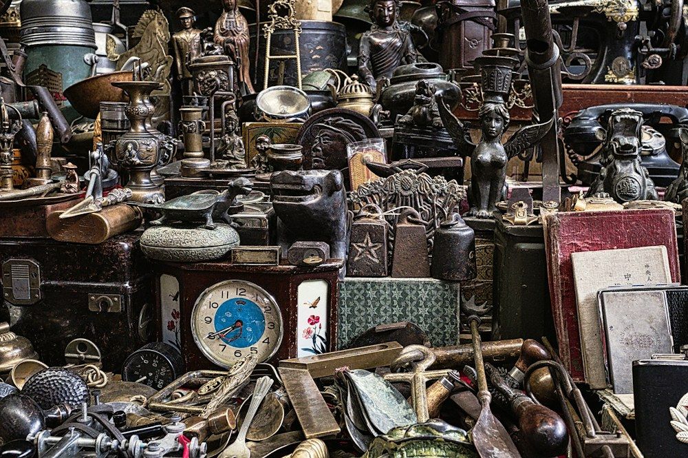 A vibrant collection of antique treasures is arranged in a tightly packed display, featuring a variety of metal trinkets, ornate figurines, and vintage clocks.